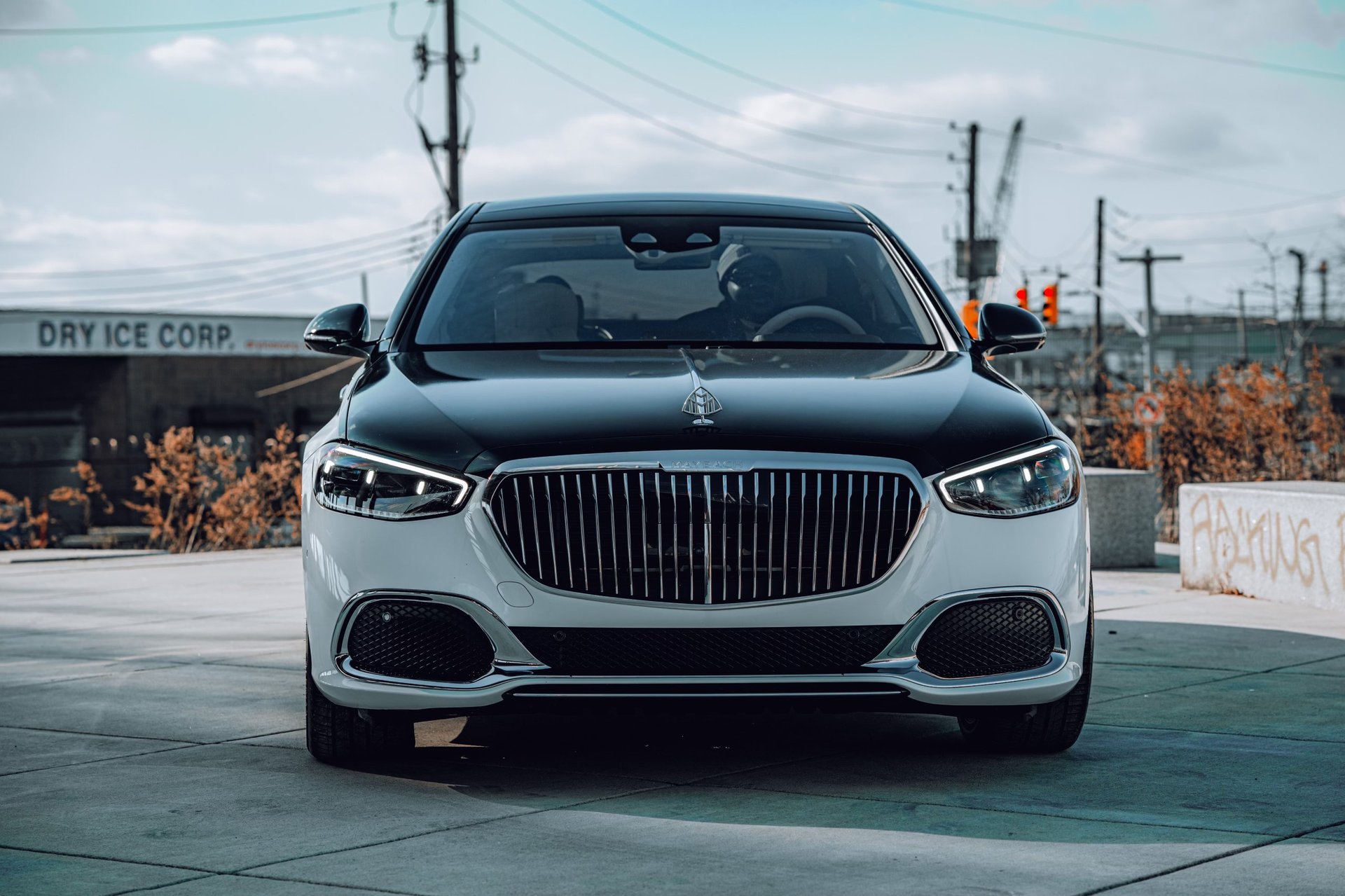 Front view of a white luxury sedan parked on a rooftop, featuring a distinctive vertical grille and LED headlights
